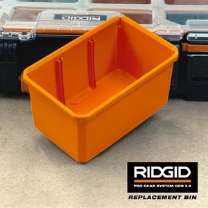 Op de afbeelding: Een feloranje rechthoekige plastic opbergbak met verticale ribbels aan de binnenzijde, ontworpen als vervangend onderdeel voor het RIDGID Pro Gear System Gen 2.0. De bak heeft een brede bovenrand en een diepe, open ruimte voor diverse items.