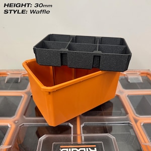 May include: An orange storage bin with a black waffle-style insert. The insert is divided into six compartments. The height of the insert is 30mm. The bin is sitting on a clear plastic surface.