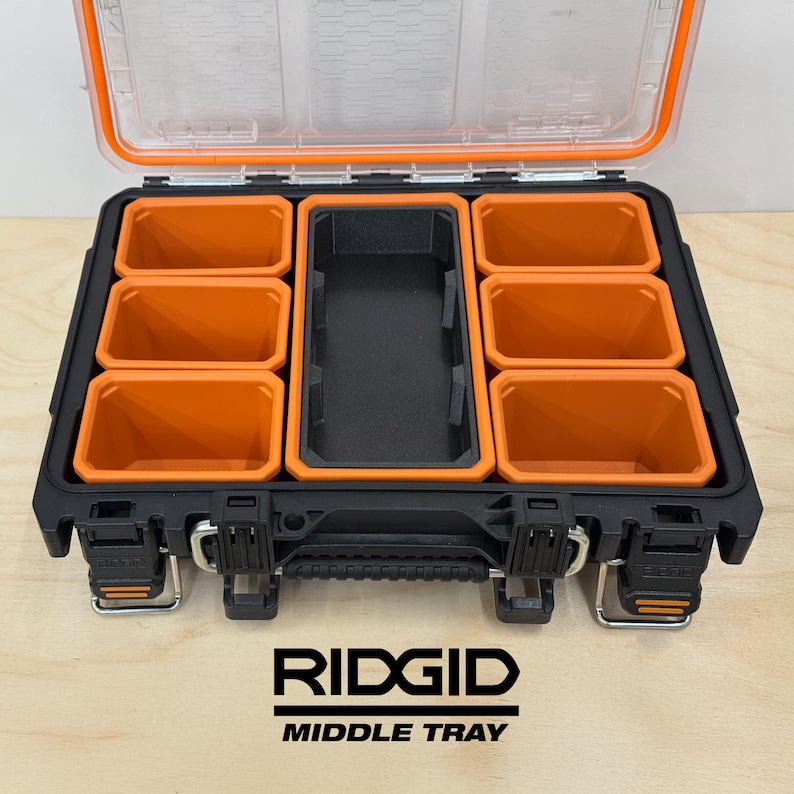 Pu&ograve; includere: Organizzatore di attrezzi RIDGID nero e arancione con vassoio centrale e coperchio trasparente. L'organizzatore ha pi&ugrave; scomparti arancioni e una sezione centrale nera. Il logo RIDGID e "MIDDLE TRAY" sono stampati.