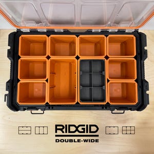 May include: Black and orange Ridgid Double-Wide tool organizer with a clear lid. The interior features multiple orange compartments and a smaller gray section. The Ridgid logo and "Double-Wide" text are visible at the bottom.