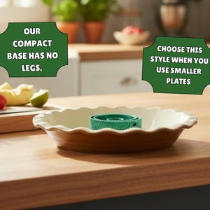 May include: A round, cream-colored pie dish with a fluted edge containing a small, green, cylindrical base. Text overlays read: OUR COMPACT BASE HAS NO LEGS. and CHOOSE THIS STYLE WHEN YOU USE SMALLER PLATES. The dish sits on a wooden surface.