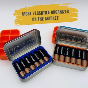 May include: Two metal Altoids tins containing black and copper Duracell batteries, with orange and blue plastic inserts. The text MOST VERSATILE ORGANIZER ON THE MARKET! is displayed in a yellow brush stroke graphic above the battery storage containers.