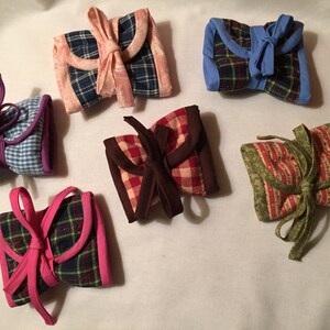 May include: Six fabric gift wrap pouches with different patterns and colors. The pouches are tied with ribbon and are ready to be filled with gifts.