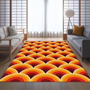 May include: A rectangular area rug with a retro design. The rug features a repeating pattern of layered, semi-circular shapes in shades of red, orange, and yellow. The rug is placed on a wooden floor in a living room setting.