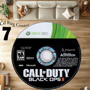 Könnte beinhalten: Eine schwarze Xbox 360-Spiel-Disc für "Call of Duty: Black Ops II" mit grünen und weißen Akzenten. Die Disc zeigt das Xbox 360-Logo, das Activision-Logo und die ESRB-Einstufung. Der Text "Cd Rug Center" und die Zahl "7" sind ebenfalls sichtbar.