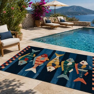 May include: A rectangular area rug featuring a dark blue background with vertical stripes and a repeating pattern of five stylized fish in shades of yellow, red, green, and blue. The rug has a checkered border in red, blue, and orange squares.