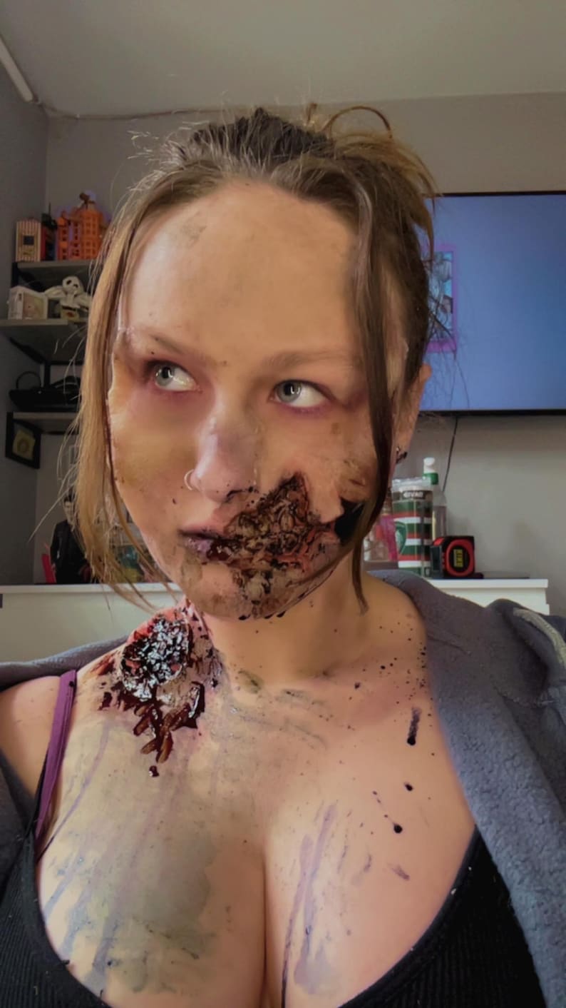 Pu&ograve; includere: Trucco da zombie su una persona, con effetti di carne esposta e gore sul viso e sul petto. Il trucco include tonalit&agrave; rosso scuro e marrone, creando un aspetto orribile e realistico. Il tema generale &egrave; l'horror e Halloween.