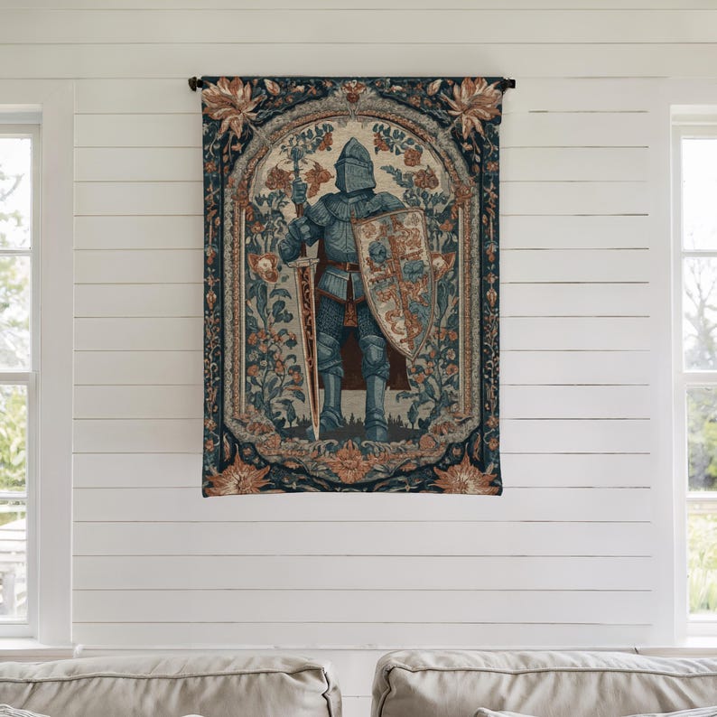 K&ouml;nnte beinhalten: Ein Wandteppich, der einen mittelalterlichen Ritter in voller R&uuml;stung zeigt, der ein Schwert und einen Schild h&auml;lt. Der Ritter ist vor einem floralen Hintergrund mit einem dunkelblauen Rand und Akzenten in Orange und Creme platziert. Der Wandteppich h&auml;ngt an einer wei&szlig;en Wand.