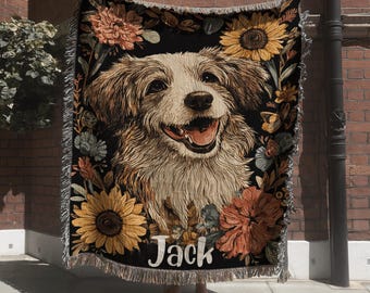 May include: A woven throw blanket featuring a central portrait of a light-colored dog with a happy expression, surrounded by a floral border of sunflowers and orange blossoms on a black background, with the name Jack printed in white text.