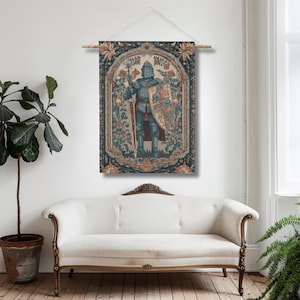 K&ouml;nnte beinhalten: Ein Wandbehang mit einem mittelalterlichen Ritter in voller R&uuml;stung, der ein Schwert und einen Schild h&auml;lt. Der Ritter ist in Blau- und Graut&ouml;nen dargestellt, umgeben von einem floralen Rand mit braunen und blauen Akzenten. Der Wandteppich ist an einer Holzstange befestigt.