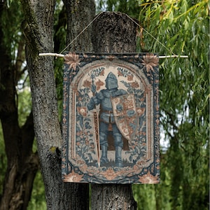K&ouml;nnte beinhalten: Ein Wandbehang im Tapisserie-Stil mit einem mittelalterlichen Ritter in voller R&uuml;stung, der ein Schwert und einen Schild h&auml;lt. Das Design enth&auml;lt florale und ornamentale Elemente in Blau-, Braun- und Beiget&ouml;nen und erzeugt eine Vintage-&Auml;sthetik. Der Banner ist an einem Holzstab aufgeh&auml;ngt.
