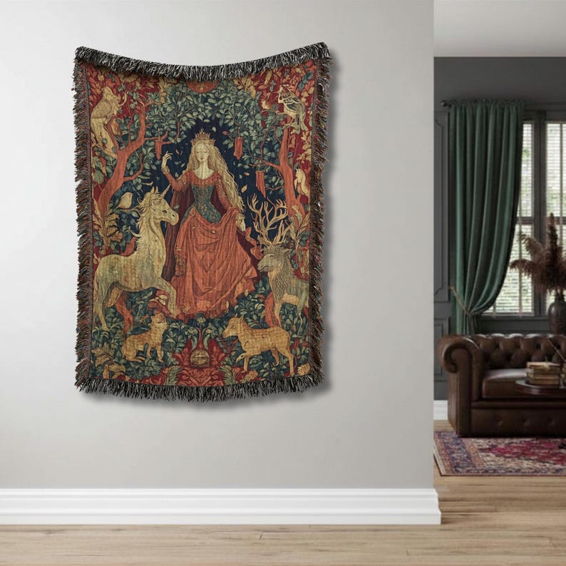 Pu&ograve; includere: Una coperta in arazzo intrecciato raffigurante una figura centrale dai capelli lunghi che indossa un abito rosso, circondata da un unicorno, un cervo e altri animali in un ambiente boschivo con toni rosso scuro, blu e verde e bordo sfrangiato.