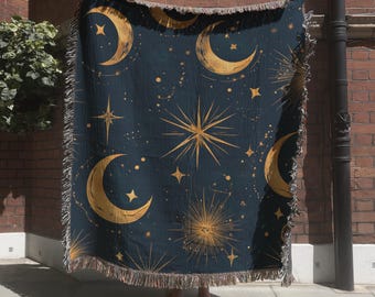 May include: A woven throw blanket featuring a dark navy blue background with a repeating pattern of golden yellow crescent moons, various sized stars, and radiating sunburst designs, finished with a decorative fringed edge on all sides.