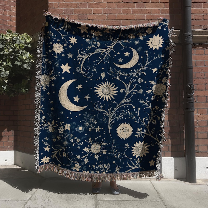 Celestial navy blue tapestry blanket featuring moons, stars, and sun motifs in an elegant vintage style. Woven throw perfect for astrology lovers, boho home decor, or cosmic-themed bedding. Cozy and mystical celestial blanket for bedroom, meditation, or spiritual spaces.