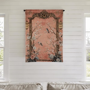 May include: A decorative wall tapestry featuring a peach-colored background with a floral and bird design. The tapestry has a dark brown ornate frame with lanterns on each side. The design includes white and pink flowers and two birds perched on branches.