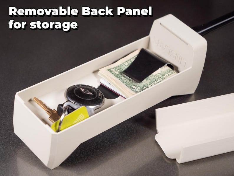 May include: A white plastic storage box with a removable back panel. The box is open and contains a money clip with cash, a key with a key fob, and a credit card. The text "STAY TIGHT" is printed on the side of the box.