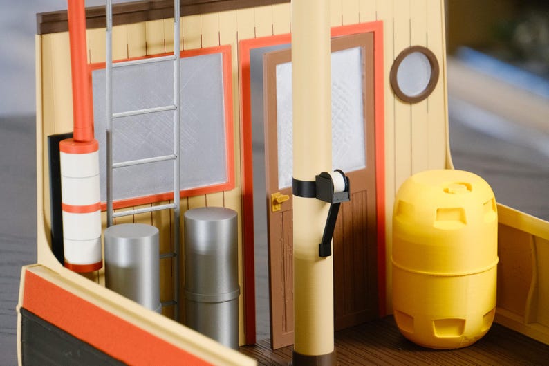 May include: A detailed model of a boat's interior, featuring a yellow and orange color scheme. The model includes a ladder, windows, a door, and a cylindrical yellow structure. The design is reminiscent of a tugboat or similar vessel.