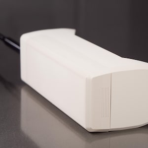 May include: A white, rectangular, cordless phone with a black antenna. The phone has a smooth, plastic surface and a small, rectangular button on the side.