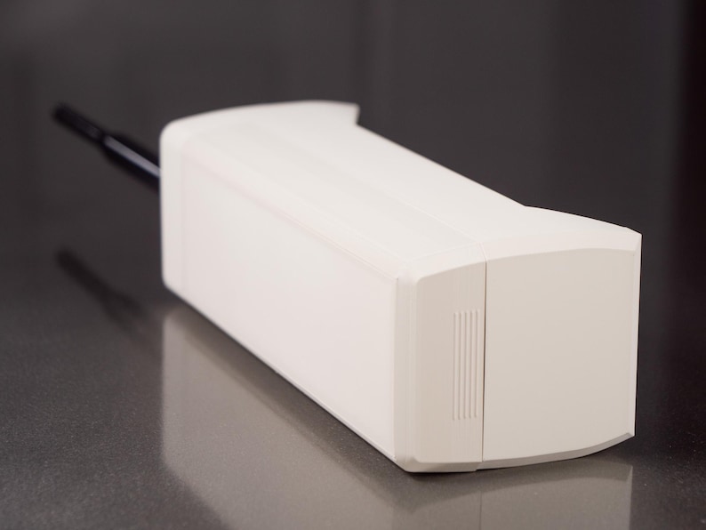 May include: A white, rectangular, cordless phone with a black antenna. The phone has a smooth, plastic surface and a small, rectangular button on the side.