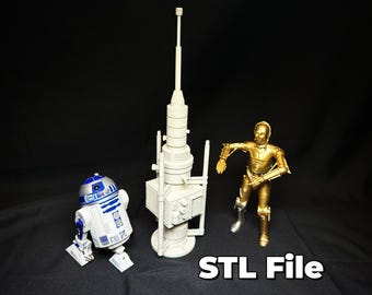 以下が含まれることがあります： 白いスターウォーズのアンテナタワーの3Dプリントモデル。金色のC-3POアクションフィギュアと青と白のR2-D2アクションフィギュアの隣に置かれています。フィギュアの下には「STL File」というテキストが印刷されています。
