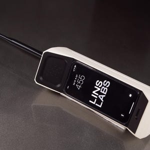 May include: A white retro-style phone with a black antenna and a black screen displaying the time 4:55 and the text "LINS LABS".