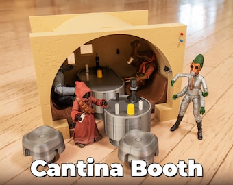 Könnte beinhalten: Ein beigefarbenes Plastikmodell einer Cantina-Kabine mit einem gewölbten Torbogen, in dem sich vier Figuren befinden. Die Figuren sind aus Plastik und in verschiedenen Farben bemalt. Die Kabine steht auf einer Holzoberfläche.