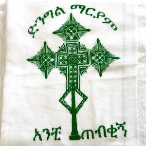 May include: White cloth with a green cross and text in a foreign language. The cross is surrounded by four stars. The text reads "እግዚአብሔር መሰረት አንተ መሰረት".