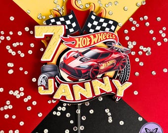 Puede incluir: Adorno para tarta con temática de Hot Wheels con el número 7, un coche de carreras rojo y el nombre "JANNY". El adorno incluye banderas a cuadros, llamas y el logotipo de Hot Wheels. El fondo es rojo, amarillo y negro.
