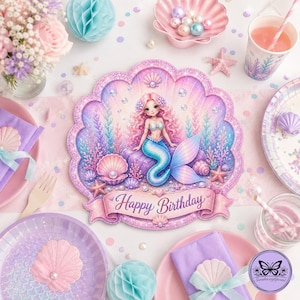 Könnte beinhalten: Ein muschelförmiger Pappteller mit gewelltem Rand, der eine Meerjungfrau mit rosa Haaren und blauem Schwanz inmitten von Korallen und Blasen zeigt. Ein rosa Banner am unteren Rand trägt den Schriftzug Happy Birthday in violetter Schreibschrift.
