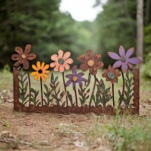 Könnte beinhalten: Eine Metall-Garten Dekoration mit einer Reihe von bunten Blumen mit grünen Blättern. Die Blumen sind in Orange-, Gelb-, Rosa-, Lila- und Blautönen bemalt. Das Stück ist aus rostigem Metall und hat einen rustikalen Look.