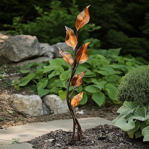 Può includere: Una scultura da giardino in metallo di una pianta stilizzata con foglie color rame. La scultura è realizzata in metallo ritorto e ha un aspetto rustico.
