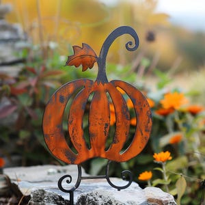 May include: An orange metal pumpkin yard decoration with a black stem and curly tendril. The pumpkin has a distressed finish and is supported by a black metal base with decorative swirls. A fall-themed garden accent.
