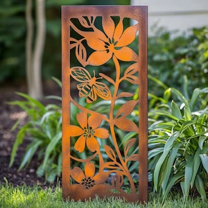 Pode incluir: Uma tela de jardim retangular de metal laranja enferrujado com desenhos recortados de flores, folhas e uma abelha. A tela é colocada em um jardim com grama verde e folhagem ao fundo.