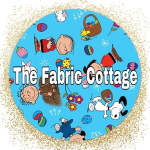 May include: A circular design with a light blue background featuring cartoon characters, Easter eggs, and flowers. The text "The Fabric Cottage" is prominently displayed in white. The design is surrounded by a gold glitter border.