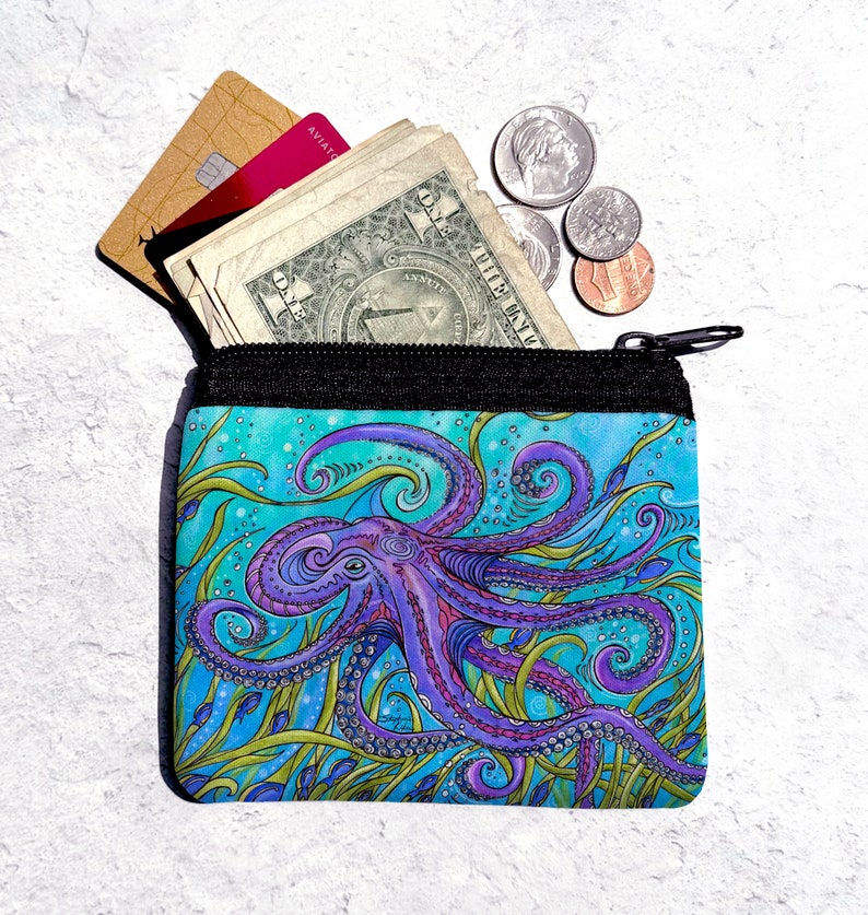 May include: A small zippered pouch with a colorful octopus design. The octopus is purple and blue with green seaweed and small blue fish. The pouch is open and has cash and credit cards inside.