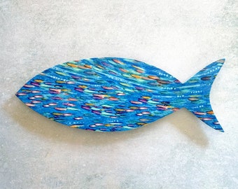 May include: A blue wooden fish sculpture with a design of many small colorful fish swimming in a school. The fish is painted in shades of blue, green, and purple.