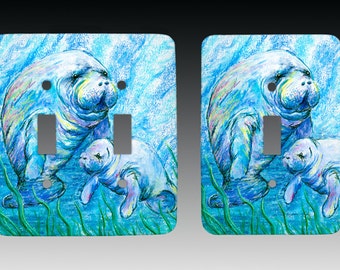 Può includere: Un paio di placche per interruttori doppi di colore azzurro chiaro con un'illustrazione colorata di due lamantini che nuotano in una scena sottomarina blu e verde.