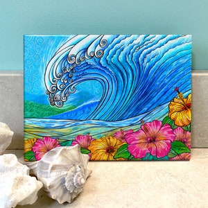 May include: A vibrant painting depicts a large, curling ocean wave in shades of blue, with white accents. The artwork features a row of pink and yellow hibiscus flowers at the bottom. The background includes a blue sky and green land.