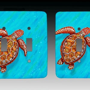 May include: Two light switch covers with a sea turtle design. The turtles are orange and brown with intricate patterns, set against a turquoise background with a watercolor effect. The covers have a rectangular shape.