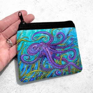May include: A purple octopus with swirling tentacles is surrounded by green seaweed and blue fish on a turquoise background. The octopus is featured on a zippered pouch.