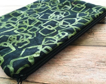 May include: A green and black zippered pouch with a geometric pattern. The pouch is made of fabric and has a black zipper.