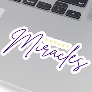 May include: Purple and gold sticker with the text "Expect Miracles" in a cursive font.