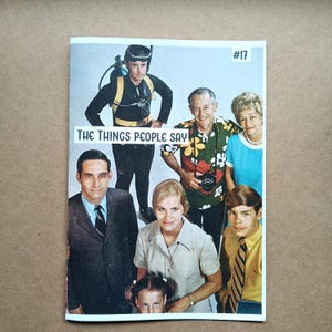 May include: A vintage magazine cover featuring a group of people. The cover includes the text "THE THINGS PEOPLE SAY" and the number "#17". The people are dressed in various outfits, including a scuba diver, a man in a suit, and a woman in a blue dress.