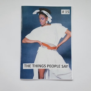 May include: A magazine cover featuring a woman wearing a white shirt and skirt with a brown belt. The cover text reads "THE THINGS PEOPLE SAY" and the issue number is #15.