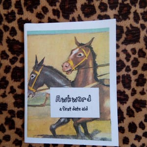 May include: A card with a humorous illustration of two horses pulling a cart. The card has the text "Awkward, a first date aid" printed on it.