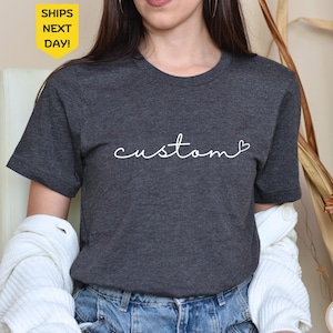 May include: A dark grey t-shirt with the word "custom" written in white cursive with a small heart after the word.