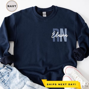 May include: Navy blue sweatshirt with the text "RN Elaina" in white on the front.