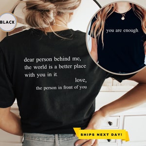 May include: Black t-shirt with white text that reads "dear person behind me, the world is a better place with you in it. love, the person in front of you".