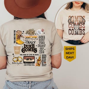 May include: Beige t-shirt featuring a graphic design with the text "Luke Combs" and other text and images. The design includes a cowboy hat, boots, and beer bottle. The shirt is a crew neck.