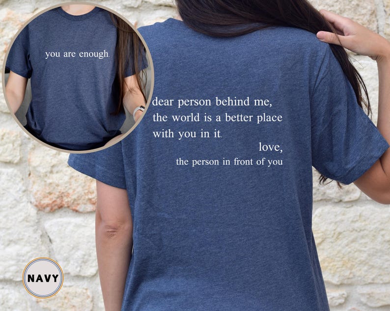 May include: Navy blue t-shirt with the text "you are enough." on the front and the text "dear person behind me, the world is a better place with you in it. love, the person in front of you" on the back.